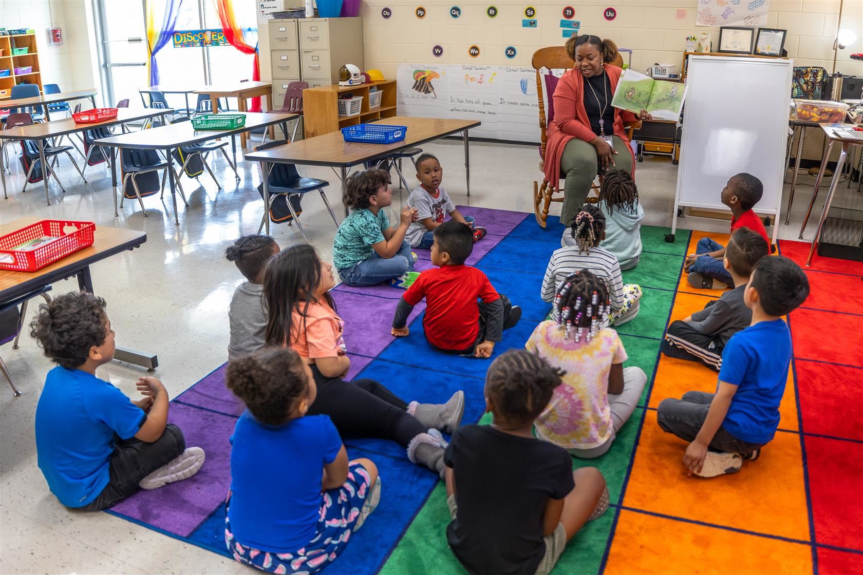 Goal 1 - Improved Early Literacy in Grades K-2 | image showing teacher reading a book to young children
